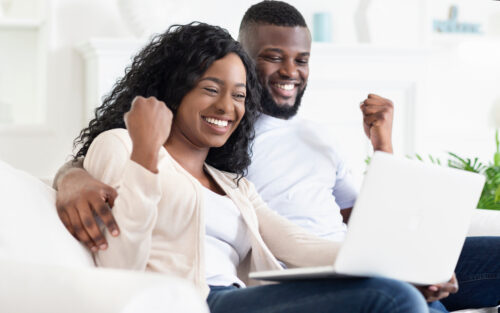 two people celebrating holding a computer