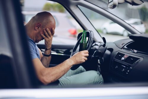 drunk driver holding alcohol behind wheel