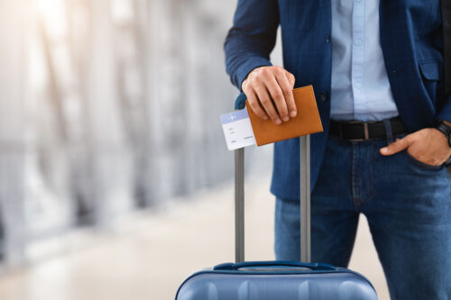 a man with holding luggage an a several documents in his hand along with a passport and a national interest waiver.