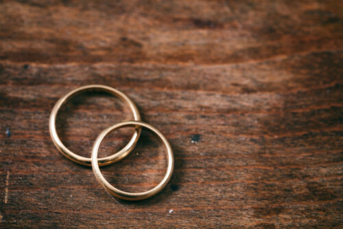 A pair of golden wedding rings on wooden background, copy space, top view