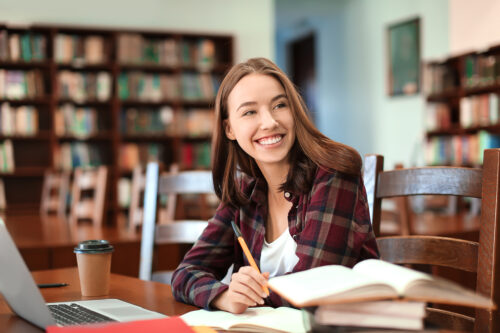 Pretty student with laptop studying in library