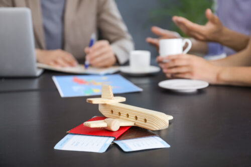 Wooden airplane with passports and tickets on table in travel agency