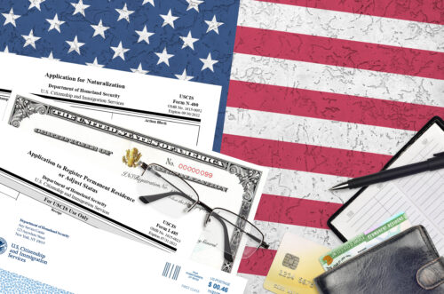 USCIS form I-485 Application to register permanent residence or adjust status and N-400 Application for naturalization with Certificate of naturalization lies on office table