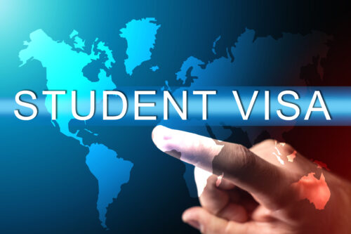 Obtaining a student visa. Human hand next to a virtual screen. Concept - services for obtaining a student visa. Admission to study at a foreign university. Student visa logo on world map background